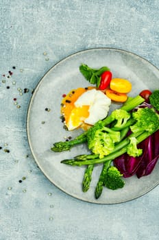 Diet salad with asparagus, poached egg and lettuce, tomato.