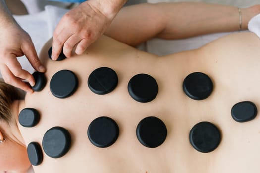 Plump woman getting hot stones arm massage in a spa salon. Therapy, wellness and relaxation concept