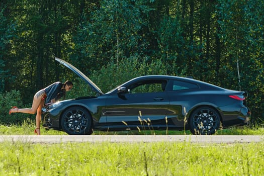 September 12, 2021, Minsk, Belarus - driver woman bent under the hood of a car