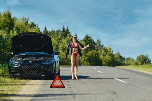 September 12, 2021, Minsk, Belarus - Sly woman in underwear draws attention to her broken-down car