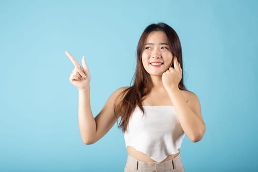 Beauty skin care. Asian beautiful young woman finger pointing to empty copy space studio shot isolated on blue background, Portrait female perfect skin point presenting for your product