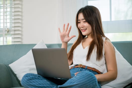 Happy woman browsing through the internet during free time on laptop computer, Female smiling sit on sofa using laptop in living room at home, girl shopping or chatting online in social media network