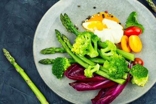 Appetizing salad with asparagus, lettuce, fresh tomatoes and poached egg. Healthy eating