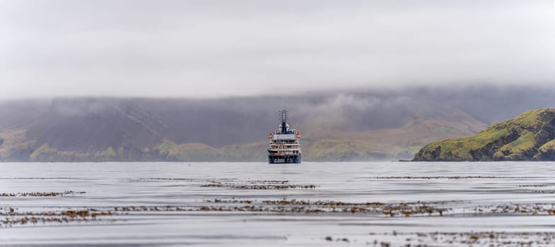 Expedition ship standing in the bay off South Georgia of Leith Harbour - old, abandoned and largest of all seven whaling stations on South Georgia.