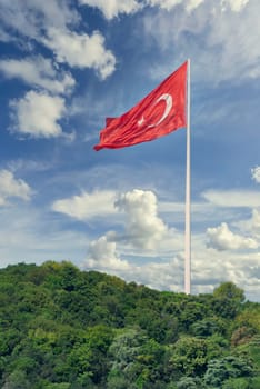 Huge Turkish flag at the mountains of Bosphorus strait, in a cloudy sunny summer day, Istanbul, Turkey