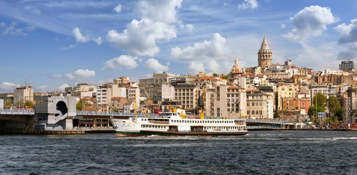Ferry boat sailing in Bosphorus Strait, with Istanbul skyline in the background, overlooking Galata Bridge with traditional fish restaurants and Galata Tower, Istanbul, Turkey
