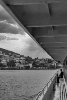 Black and white of water side passage of ferry boat on Marmara sea, with man sitting on a bench at the far end, Istanbul, Turkey