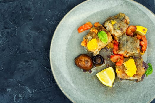 Diet fish hake cooked with mushrooms, orange and tomatoes. White fish in the oven dish