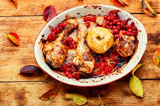 Chicken legs baked in a baking dish with apple and berries. Autumn meat recipe.