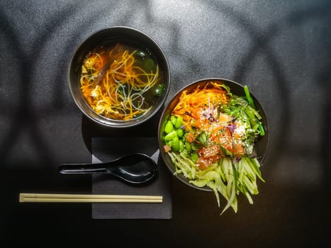 Lunch in Asian style. Shiro miso soup and poke bowl with salmon, cucumbers, green beans, carrots and chukka salad