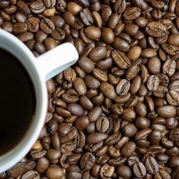 roasted coffee beans and a cup with coffee on a table