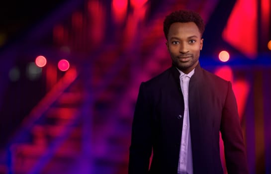 man at night outside wearing black suit urban lifestyle businessman red and blue lights city nightclubs