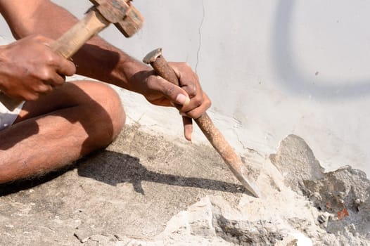 Close up Part of a construction labor working with hammer and Chisel in a construction site.