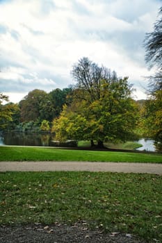 Frederiksborg Castle Park in autumn with mighty deciduous trees on the garden meadows. Colorful colors of the leaves. Walk in Denmark