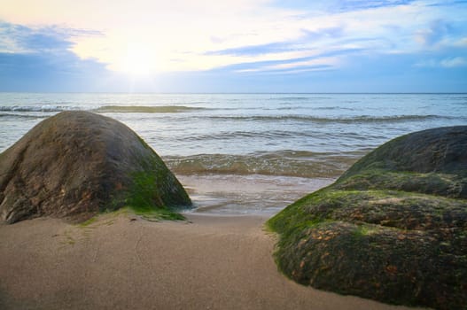 Big stone on the sandy beach in front of the sea with clouds in the sky. Denmark in Scandinavia. Landscape shot from nature in the north