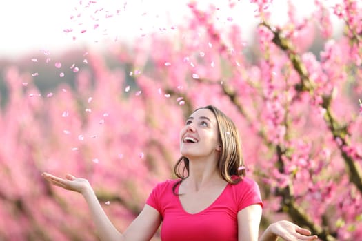 Happy woman throwing pink petals to the air in a field