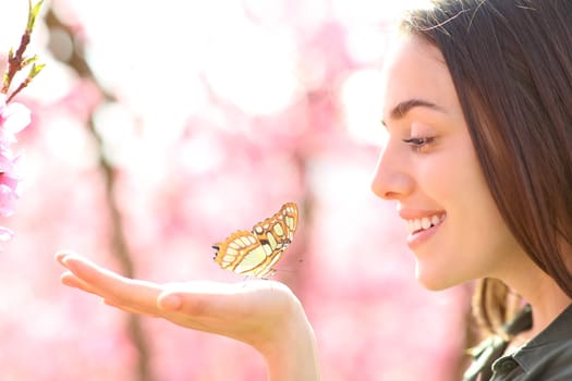 Happy woman with a butterfly in the hand looking it
