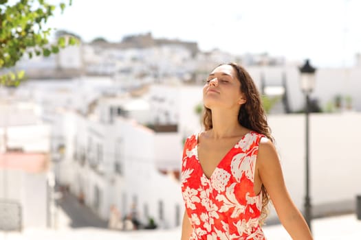 Relaxed tourist breaths fresh air in a white town on summer vacation