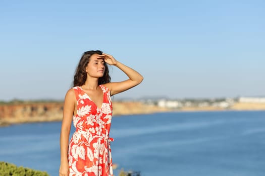 Tourist searching with hand on forehead on the beach on summer vacation