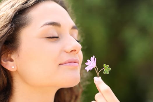 Happy woman smelling flower in a park