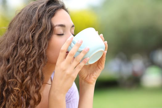 Woman drinking coffee from mug in a park