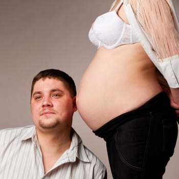man is trying to listen his baby inside of his pregnant wife