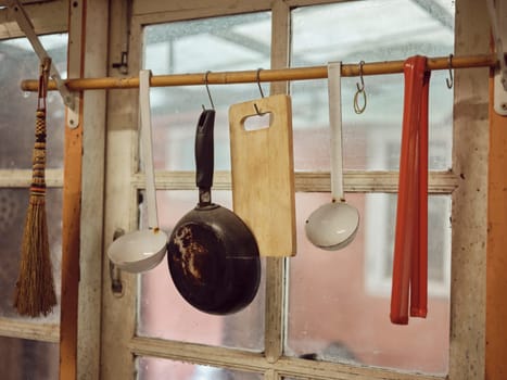 Old kitchen ware hanging on the bar. Different size of pans and kitchen ware on the wall, Home decoration, Kitchen background.