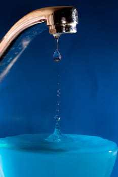Water tap with drop, on the blue background.