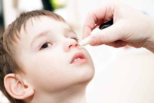 ill boy with flu and drops in the nose