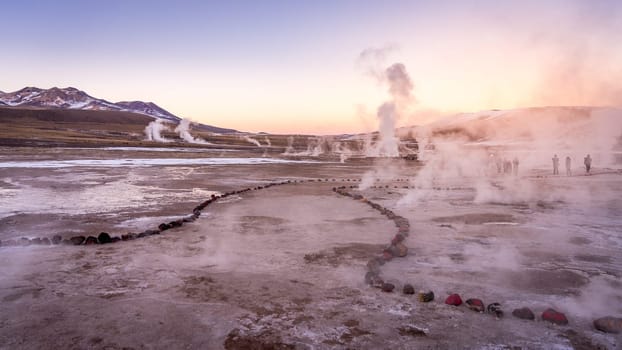 Sunrise at Geyser El Tatio near San Pedro de Atacama in Chile. Landscape with gas smoking and people in backlight.