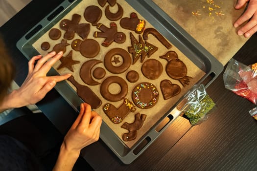 Top view of a baking sheet with ginger biscuits of different shapes while decorating.