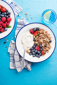 A plate of dry granola served with fresh berry fruit and yogurt. Oatmeal plate. Healthy food, diet. Top view.