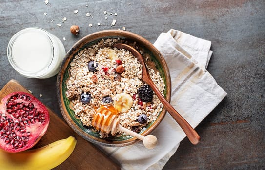 A bowl of muesli served with fresh fruit nuts and honey. Oatmeal plate. Healthy food, diet. Top view.