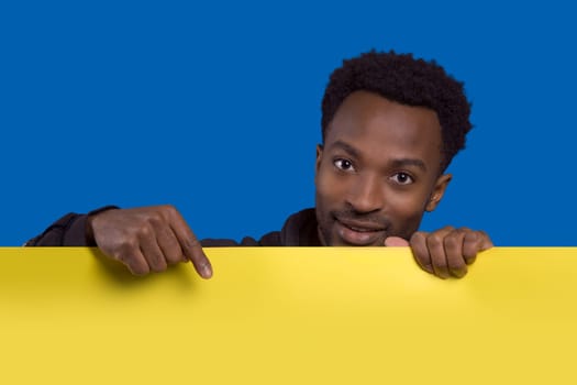 man holding and pointing board copy space background presentation banner poster yellow cardboard on blue background