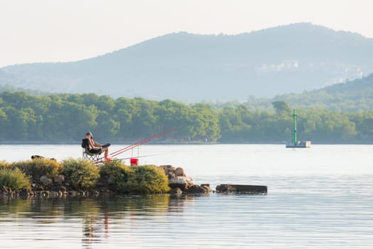 young man is sitting and fishing on canal of sveti ante in sibenik croatia