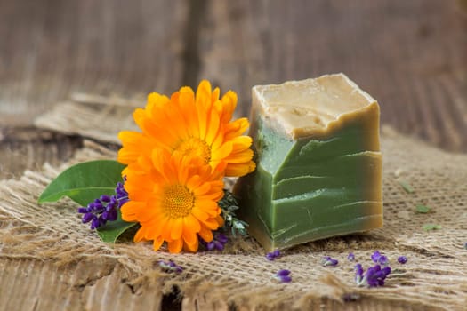 Natural handmade soap with calendula, lavender and herbs on rustic wooden background