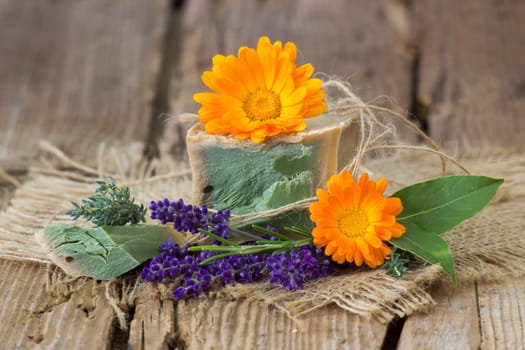 Natural handmade soap with calendula, lavender and herbs on rustic wooden background