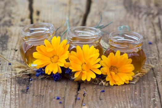 honey and calendula flowers on old wooden  background