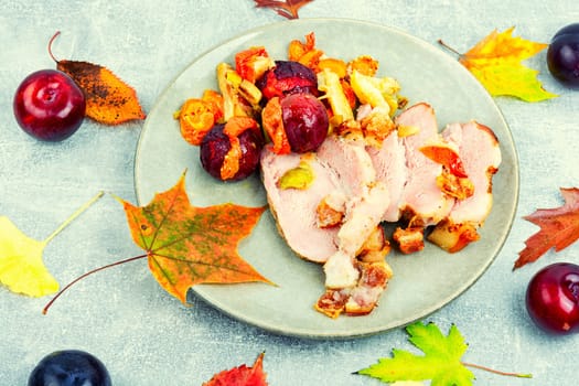Piece of pork shoulder baked in the oven with vegetables and plums.