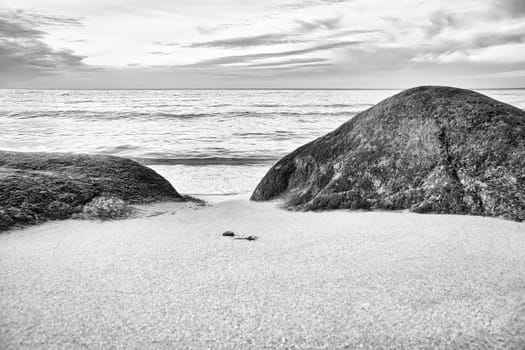 Big stone on the sandy beach in front of the sea with clouds in the sky. Denmark in Scandinavia. Landscape shot from nature in the north