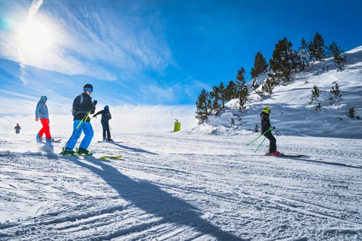 Group of people skiing and snowboarding down the ski slope or piste in Pyrenees Mountains. Winter ski holidays in El Tarter, Grandvalira, Andorra