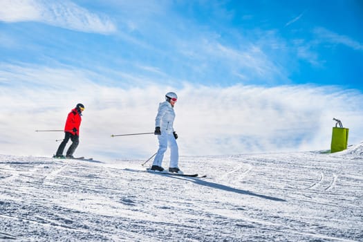Couple, man and woman skiing down the ski slope or piste in Pyrenees Mountains. Winter ski holidays in El Tarter, Grandvalira, Andorra