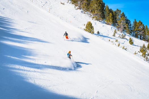 Closeup on couple of skiers going fast on steep piste or ski slope in Pyrenees Mountains. Winter ski holidays in El Tarter, Grandvalira, Andorra