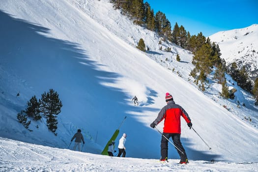 Groups of people on slope junction with focus on fast skier on steep piste in Pyrenees Mountains. Winter ski holidays, El Tarter, Grandvalira, Andorra