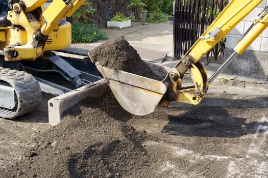 Repaving the road, The excavator is leveling gravel on the road, making a base for laying the asphalt.