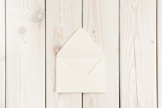 White craft handmade opened paper envelope laying on white wooden plank background. Post card message, letter sending. New delivery and traditional invitation. Copy space, mockup, clipping path