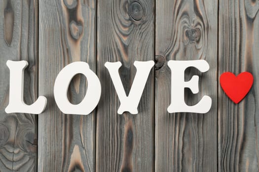Close up of white plastic or wooden letters forming word love, red paper heart near the word. Love and care fore st Valentines day, 8 march, birthday or mother day. Top view, flat lay, copy space