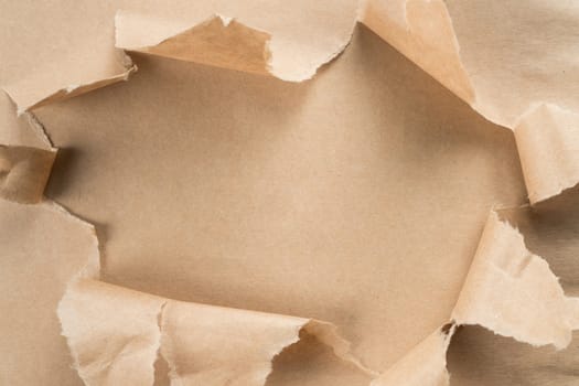 Beige crumpled packaging paper unwrapping from center, ragged paper. Unpacking and bursting from the center. Presents for holidays. Sustainable resource, eco friendly. Overlay, copy space, top view
