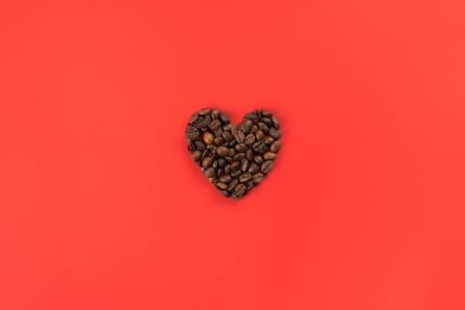 Coffee beans forming heart shape on red studio background. Charity and donation on holidays. I give you all my heart. Falling in love and confession on saint valentines day. Flat lay, copy space