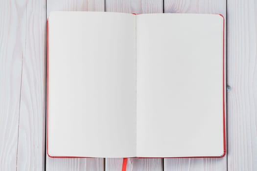 Red diary, text book with white paper pages on wooden table background. Making notes in empty workbook on office desk. Personal organizer as reminder. Blank and template. Copy space, flat lay